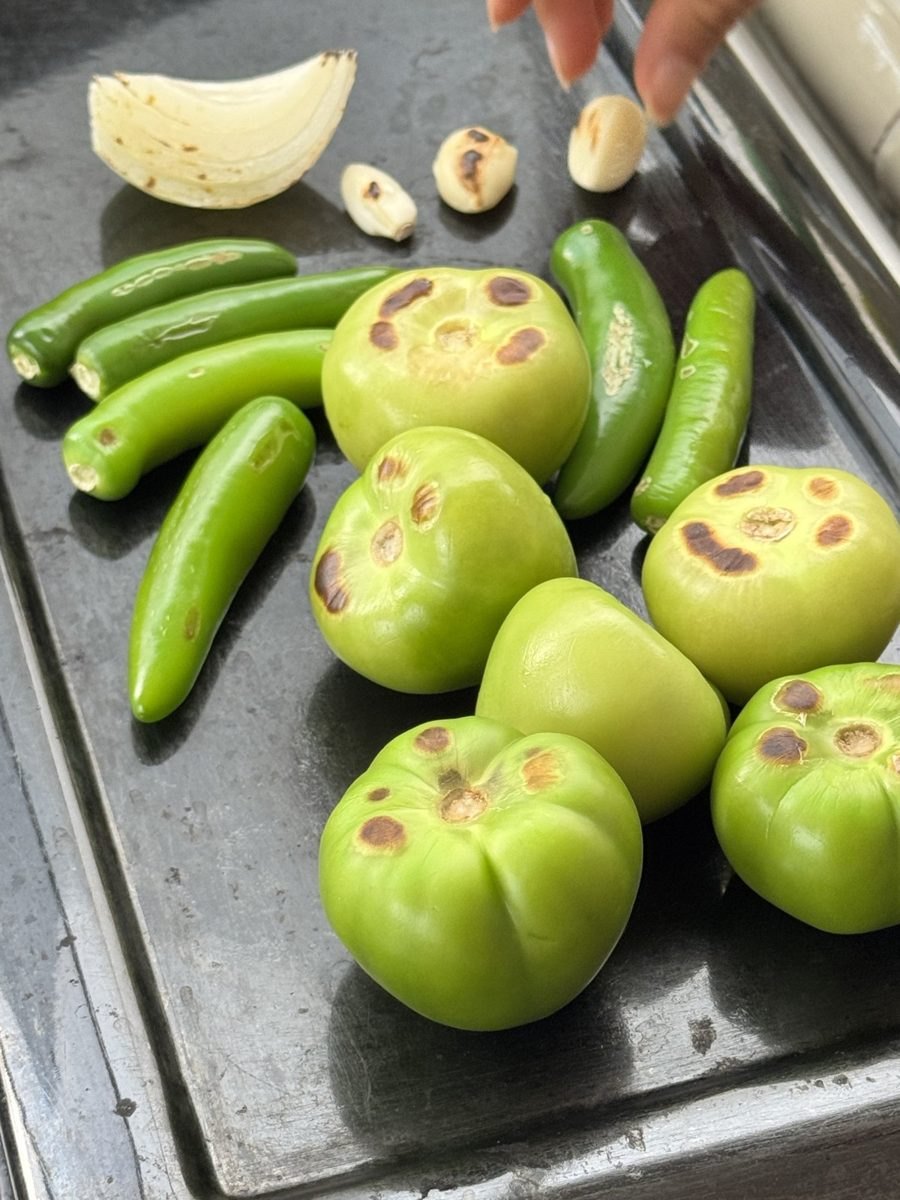 Chiles serranos y tomates verdes tatemándose en el comal